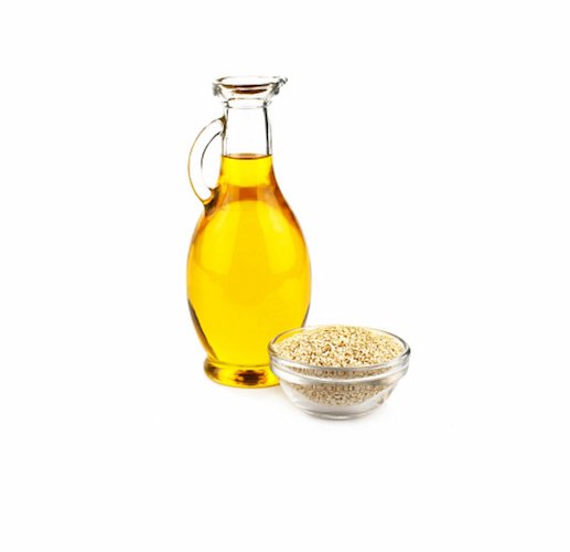 sesame oil bottle beside a cup of sesame seeds on white background.